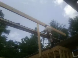 Carpenter setting a ridge beam over a new addition frame — Ice Dam Removal by Roofing Brothers in Anchorage