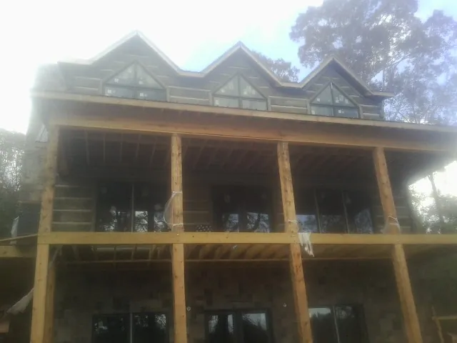 Dormers and porch framing on a large log home under construction — Roof Coating work by our crew in Anchorage