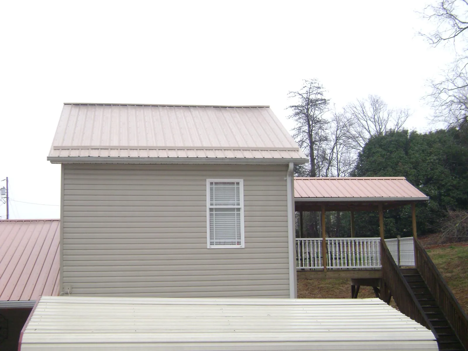 Tan metal roofs on a two story addition and attached porch, from a Roof Replacement job in Anchorage