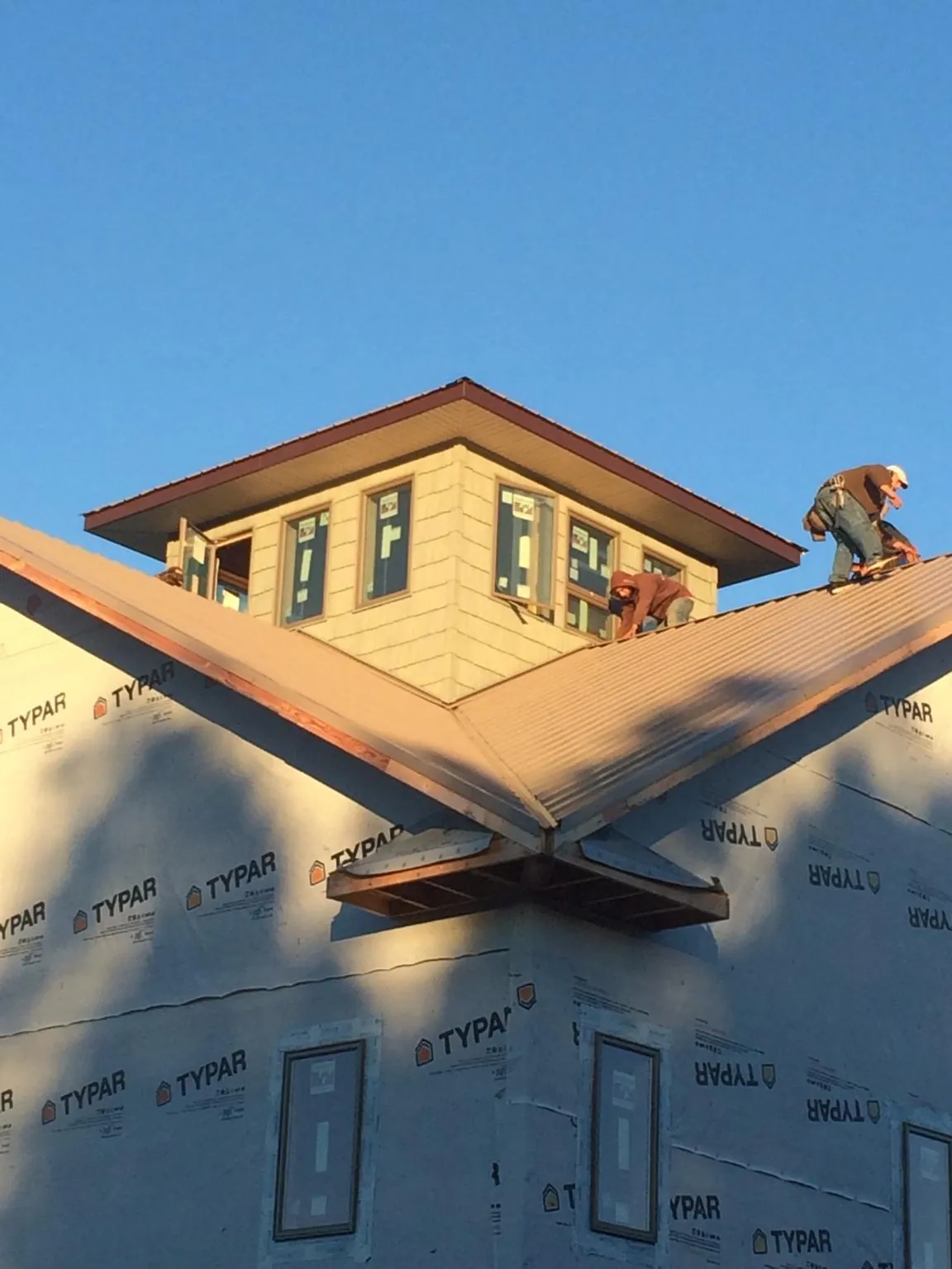 Roofers working around a rooftop cupola on a new metal roof at sunset — Roof Waterproofing in Anchorage by Roofing Brothers